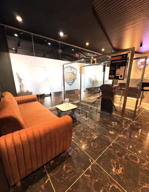 Orange lounge sofa beside the glass turnstile entrance at Jaguar Fitness Den